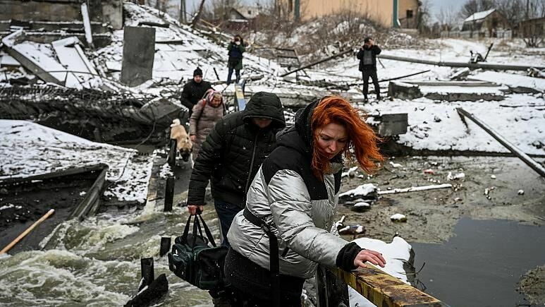 Мирные жители переходят реку по взорванному мосту на северном фронте Киева 1 марта 2022 г.