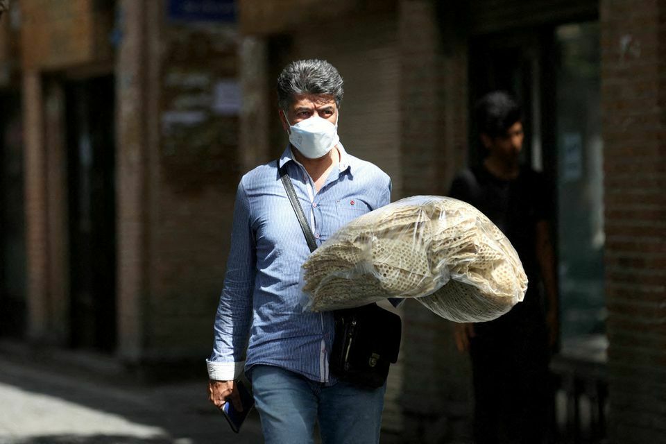 An Iranian man holds stacks of bread as he walks along a street in Tehran, 